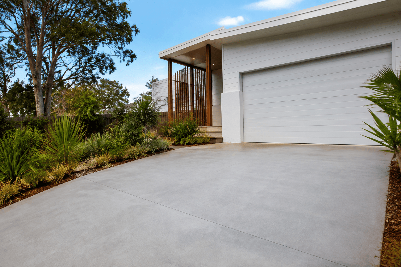 pale concrete driveway beside a Queensland coastal home and native garden